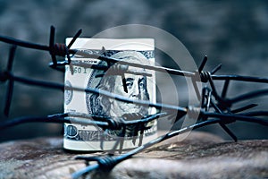 Economic warfare, sanctions and embargo busting concept Barbed wire against US Dollar bill