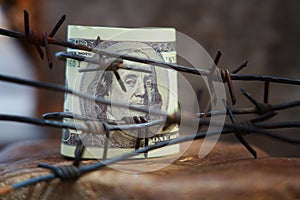 Economic warfare, sanctions and embargo busting concept Barbed wire against US Dollar bill. Horizontal image