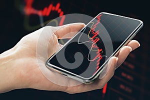 Economy crisis and mobile trading concept with falling down red financial chart candlestick on smartphone screen in human hand on