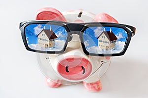 Economy and finance - piggy bank with glasses and dreamed house