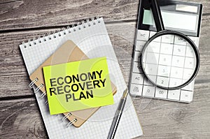 ECONOMY RECOVERY PLAN CONCEPT. Text on business paper on office table with office supplies