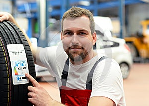 Economy sticker with consumption values on a new car tyre - changing tyres in the workshop by mechanical means