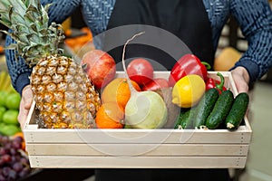 Ecoproduct. A set of fresh vegetables and fruits in a box, which the man holds in his hands. The man in the apron photo