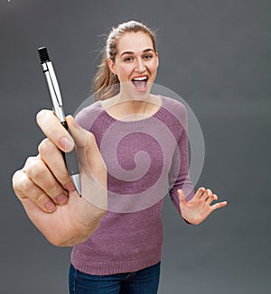 Ecstatic beautiful young woman laughing, showing pen to win contract