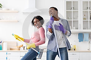 Ecstatic black couple imitating rock stars while cleaning house