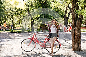 Ecstatic blonde girl in black shorts posing near bicycle. Outdoor photo of gorgeous caucasian lady
