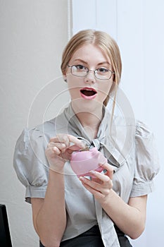 Ecstatic business woman inserting coin in a piggy bank.