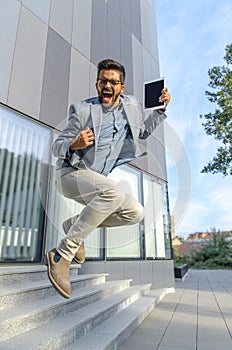 Ecstatic businessman jumps in front of office building