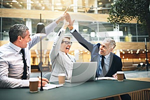 Ecstatic businesspeople high fiving each other in an office