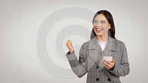 Ecstatic businesswoman with phone celebrating good news