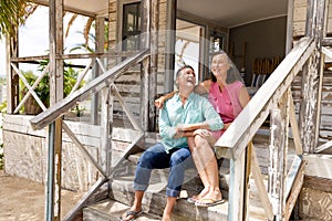 Ecstatic caucasian senior couple talking and laughing while sitting on staircase outside cottage