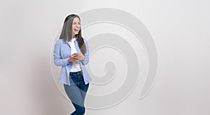 Ecstatic female professional messaging online over smart phone and laughing against white background