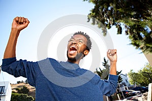 Ecstatic handsome man celebrating with arms outstretched