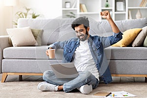 Ecstatic indian man with laptop celebrating victory or good news