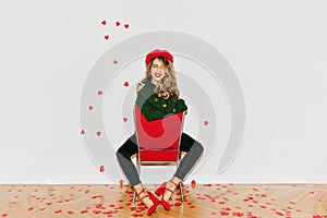 Ecstatic long-haired european girl in beret sitting on red chair. Indoor photo of pleased brunette lady in soft green