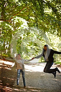 Ecstatic love. a young man jumping for joy while walking with his girlfriend in the park.