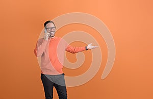 Ecstatic male entrepreneur sharing good news over phone call and gesturing against orange background