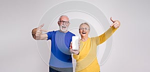 Ecstatic senior couple screaming and pointing at blank screen of mobile phone over white background