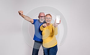 Ecstatic senior couple screaming and showing blank screen of smart phone against white background