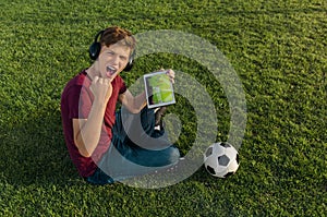 Ecstatic teen, soccer fan holding tablet