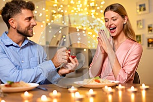 Ecstatic woman reacting to a marriage proposal at a candlelit dinner