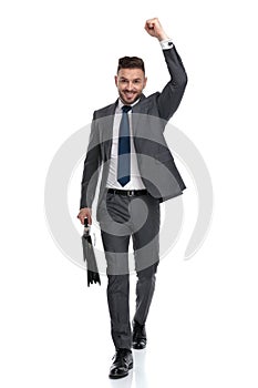 Ecstatic young businessman walking with suitcase and celebrates success