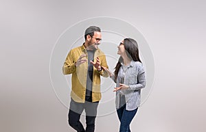 Ecstatic young partners laughing and discussing new project while standing against white background