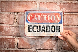 Ecuador. Caution sign in a woman& x27;s hand on a brick background
