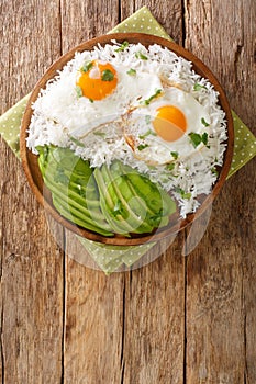 Ecuadorian simple breakfast of boiled rice and fried eggs close-up in a plate. vertical top view photo