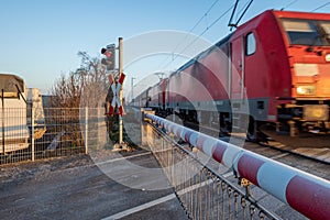 Ed and white level crossing railway barrier covered with frost which block the road on countryside.