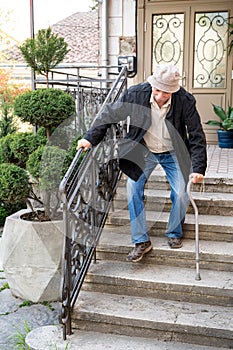 Ederly man with a cane descends down the stairs