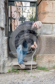 Ederly man in protective mask with a cane descends down the stairs