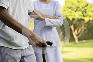 Ederly man with walking stick and nurse holding patient`s hands