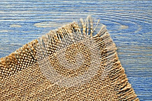 Edge of burlap cloth on a blue table