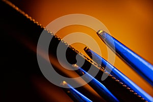 Edge of an illuminated  serrated knife and prongs of a fork macro shot suitable as a background