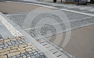 The edge of the road is drained by longitudinal channels of granite grids with gray slits at the deceleration retarder where the photo