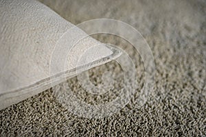 Edge tip view of white cushion on beige carpet.
