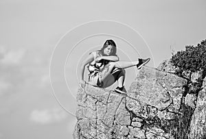 On edge of world. Woman sit on edge of cliff in high mountains blue sky background. Hiking peaceful moment. Enjoy the