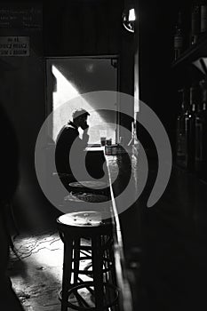 An edgy, shadowfilled cafA  scene where a notorious manspreader sits, while nearby, a disillusioned employee quietly quits photo