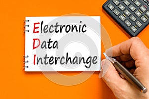 EDI electronic data interchange symbol. Concept words EDI electronic data interchange on white note. Beautiful orange background.