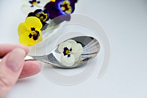 Edible flowers - Pansy, spoon with flowers on white . the concept of healthy eating, vegetarian and natural food.
