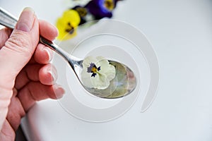 Edible flowers - Pansy, spoon with flowers on white . the concept of healthy eating, vegetarian and natural food.