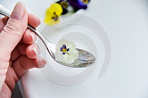 Edible flowers - Pansy, spoon with flowers on white . the concept of healthy eating, vegetarian and natural food.