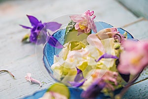 Edible flowers salad in a plate on blue wooden table with fork