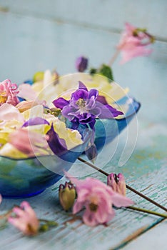 Edible flowers salad in a plate on blue wooden table with fork