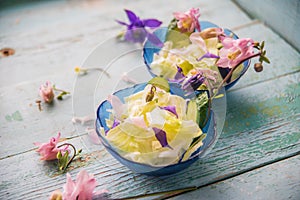 Edible flowers salad in a plate on blue wooden table with fork