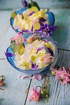 Edible flowers salad in a plate on blue wooden table with fork
