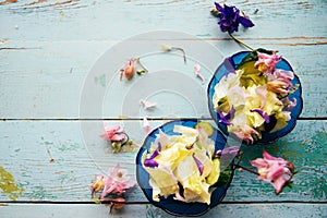 Edible flowers salad in a plate on blue wooden table with fork