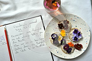 Edible flowers snacks with flower tea as a healthy and happy breakfast with journal and pen