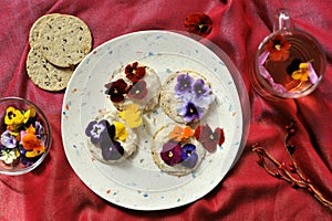 Edible flowers snacks with flower tea as a healthy and happy breakfast on a red background